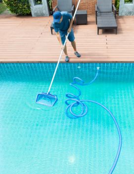 Persona limpiando una piscina con una red